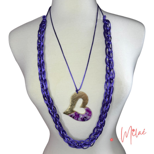 Collar hecho a mano color violeta y dije en forma de corazón. Dos collares en uno. Cierre en nudo macramè y son individuales. Tamaño mediano.